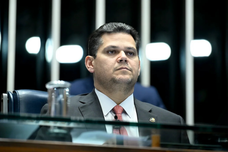 Foto do presidente do Senado, Davi Alcolumbre (União-AP), sentando em sua mesa, com a expressão séria.